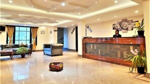 A spacious lobby with a reception desk, sofas, and a staircase.