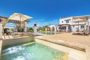 A swimming pool area with lounge chairs and umbrellas, surrounded by a poolside deck and a building with a white facade. - 3769 Tenuta La Cornola by Barbarhouse (Taurisano)