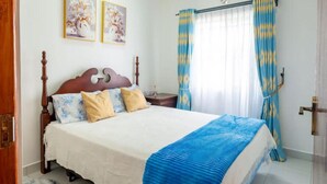 Ein Schlafzimmer mit einem hölzernen Bett, einem flauschigen Teppich und Vorhängen.