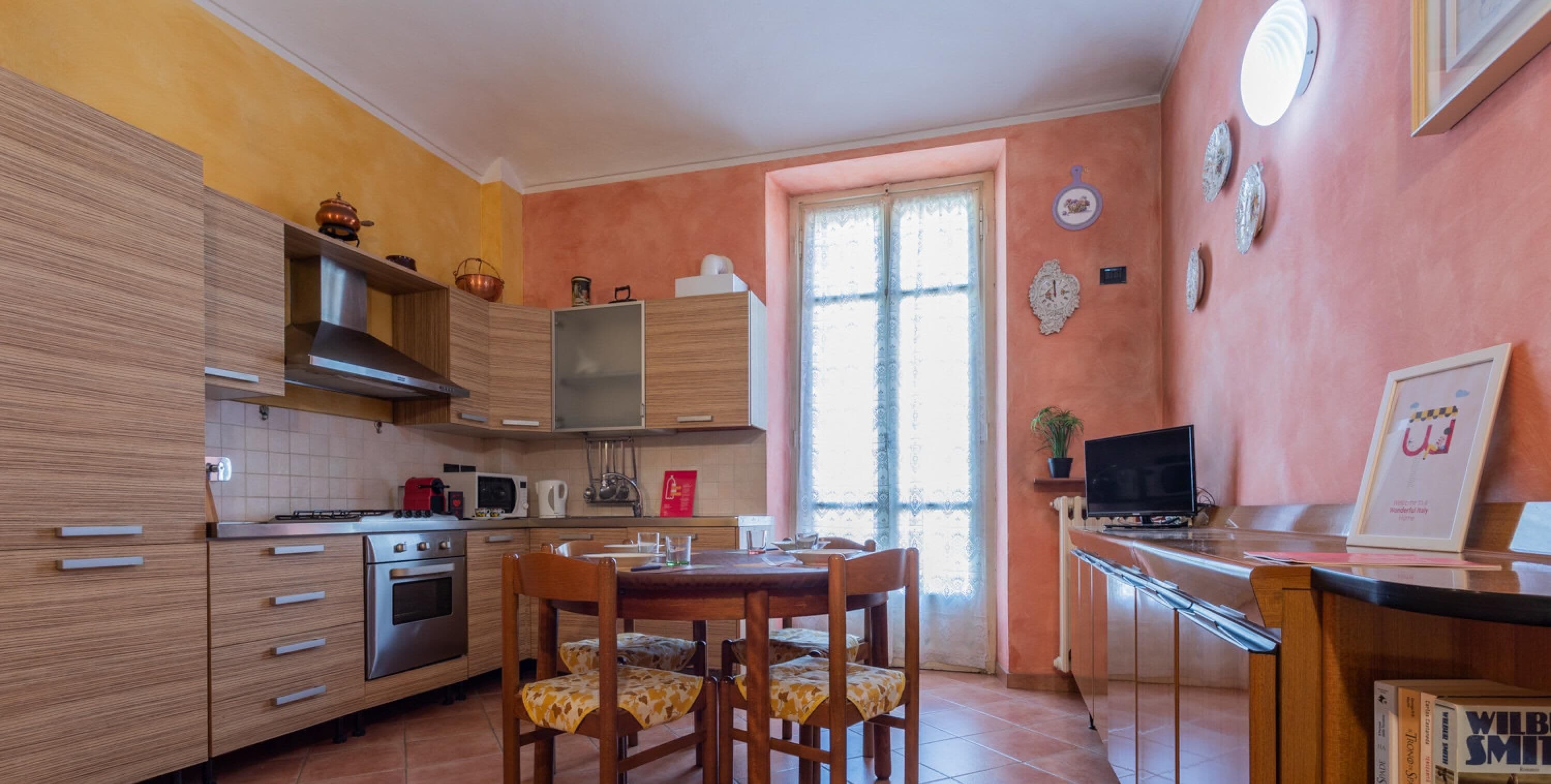 A kitchen with wooden cabinets, a stove, microwave, and a dining table with chairs.