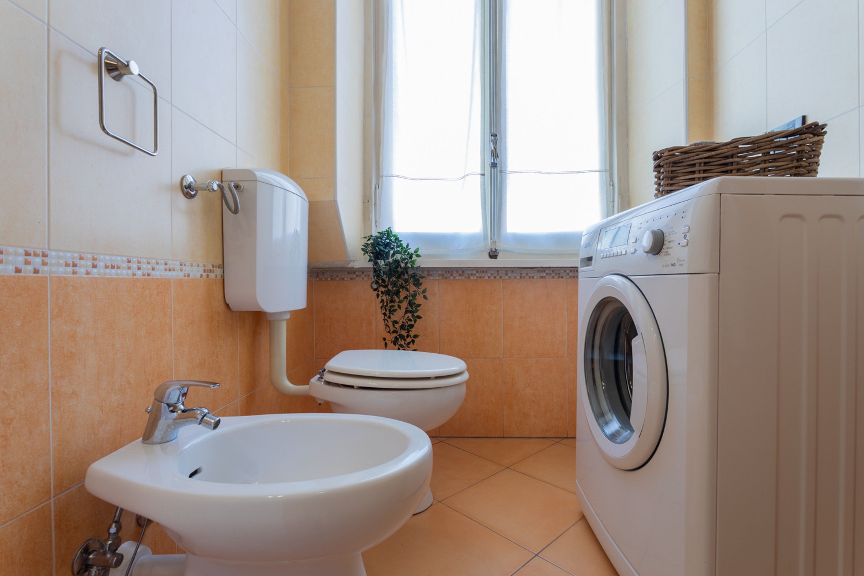 Un baño con lavamanos, inodoro y lavadora.