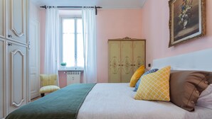 Een slaapkamer met een bed, een kledingkast, een stoel en een raam met gordijnen.