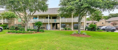 A two-story building with a covered patio and a well-maintained lawn.