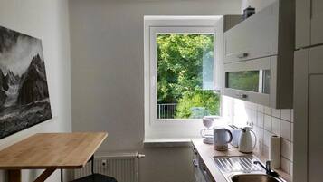 Eine kleine Küche mit Fenster, Heizkörper, Spüle und einem Tisch.