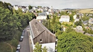 Ein ländliches Dorf mit traditionellen Häusern, einer Hauptstraße und geparkten Autos.