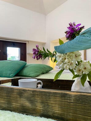 A bedroom with a bed, green pillows, a white mug, and a vase with flowers. - Il Camino Felice - 201 Autodromo F1 Villa Reale (Monza)