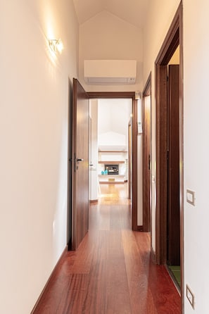 A hallway with wooden flooring, a fireplace, and a ceiling-mounted air conditioning unit. - Il Camino Felice - 201 Autodromo F1 Villa Reale (Monza)