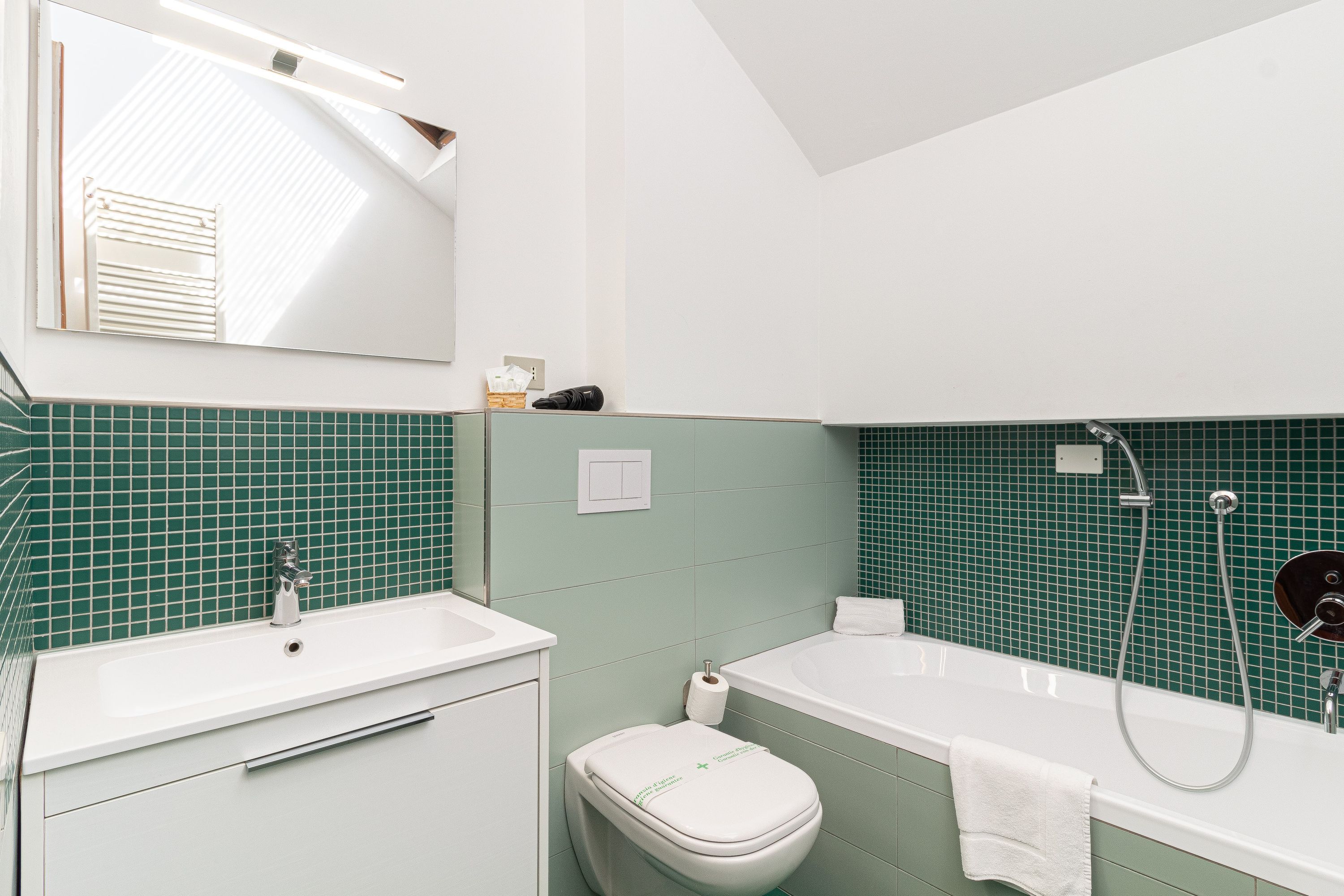 Een badkamer met een wit wastafelmeubel, toilet en bad.