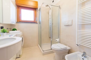 A bathroom with a glass-enclosed shower, a toilet, a bidet, a sink, and a window above the mirror. - La Terrazza di Giotto - 501 (Lissone)