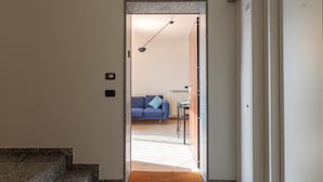 A doorway leading to a living area with a blue sofa, a small table, and a lamp. - La Terrazza di Giotto - 501 (Lissone)