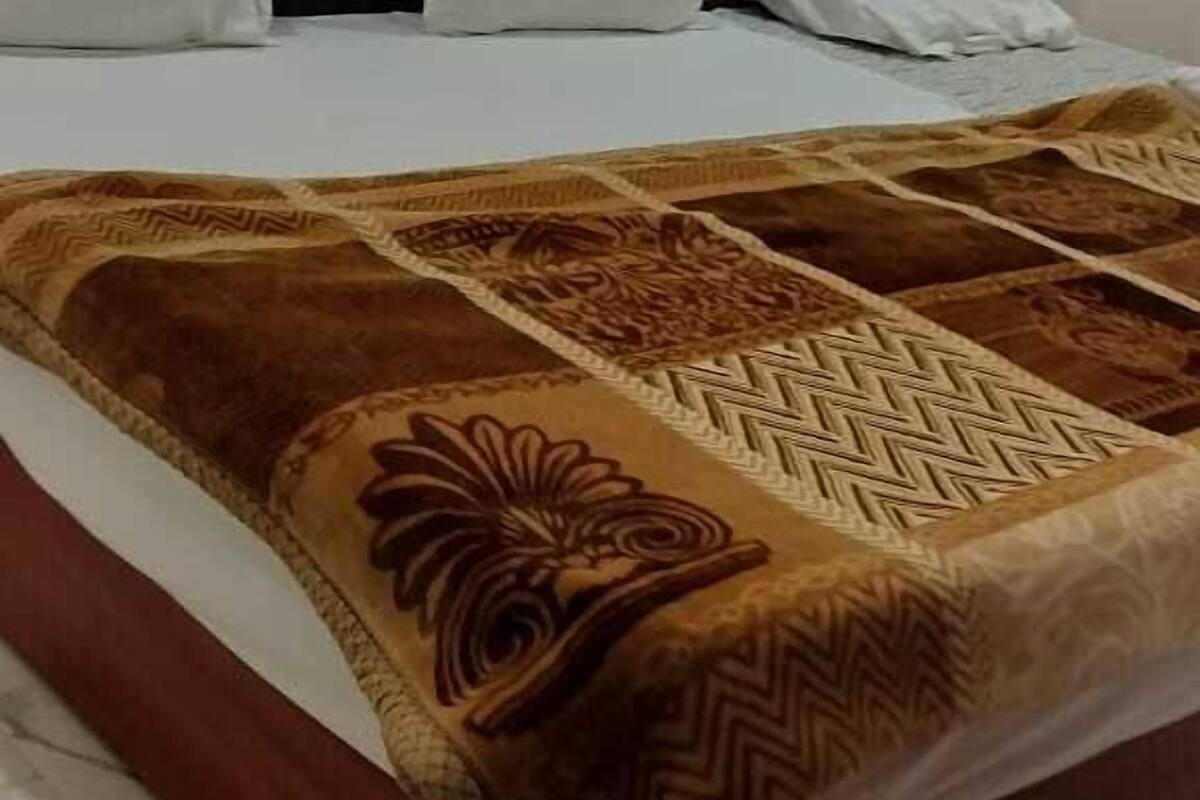 A bed with a patterned bedspread, a headboard, and white pillows.