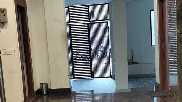 Un'ampia sala con pavimento in marmo lucido, un cancello in metallo e un soffitto con faretti.
