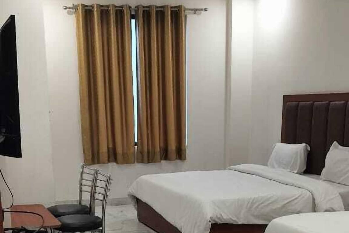 A hotel room with a bed, a desk, a chair, and a window with curtains.