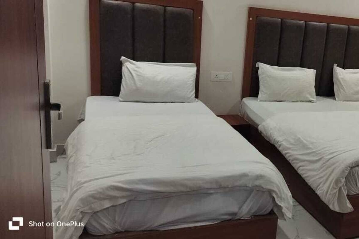 Two single beds with wooden headboards and white bedding in a room with a door and a curtain.