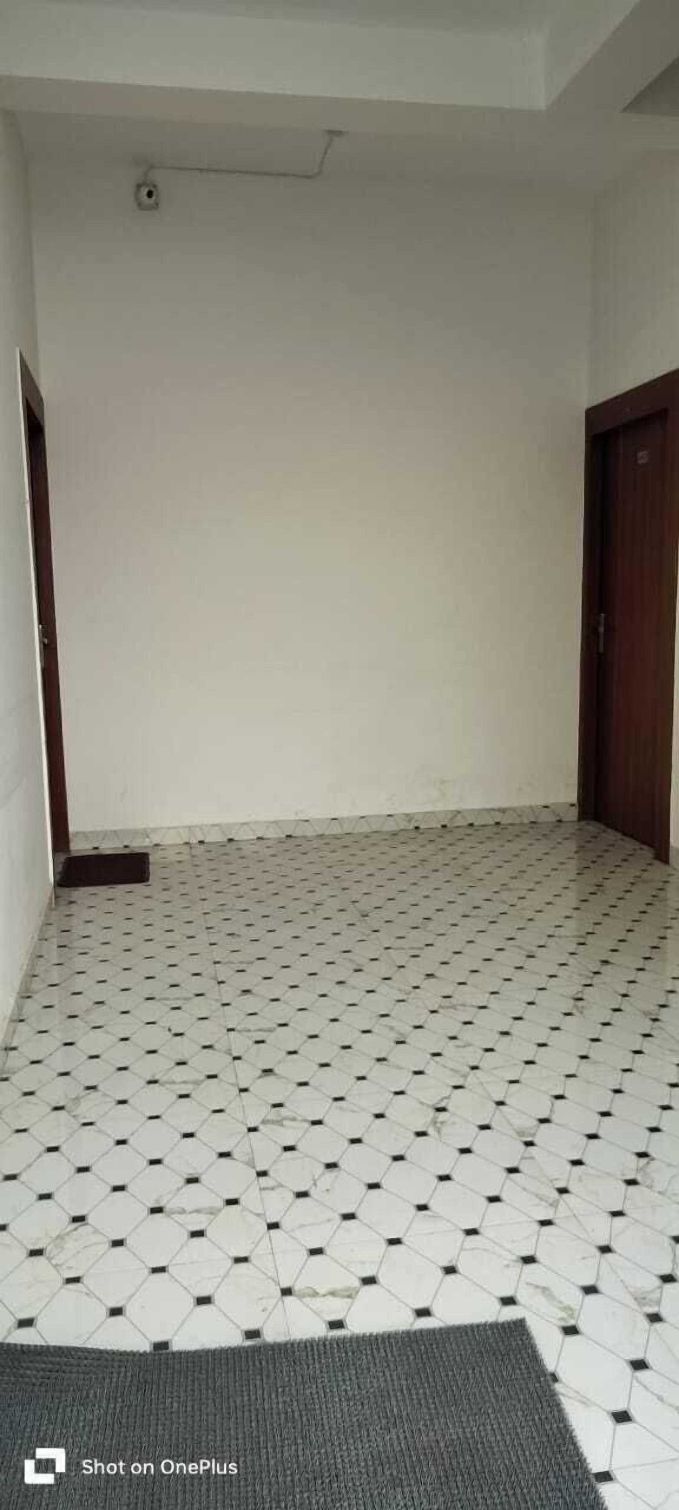 A room with a tiled floor, a door, and a vent on the ceiling.