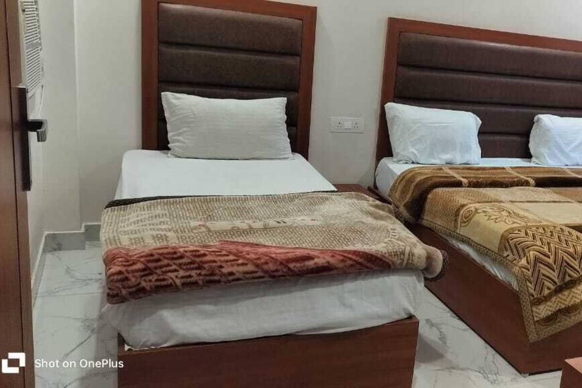 A hotel room with two beds, each with a headboard and pillows.
