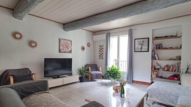 A living room with a TV, sofas, a coffee table, and a bookshelf. - Coeur de Fitou : Maison de Village Atypique (Fitou)