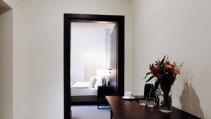 A hotel room with a wooden desk, a vase of flowers, a coffee maker, and a bed with a nightstand. - Green Krupnicza (Kraków)