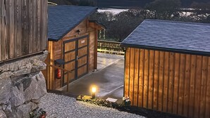 A wooden building with a stone wall, a gravel pathway, and a view of a valley at dusk.