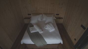 Una habitación con paneles de madera, una cama, almohadas y toallas.