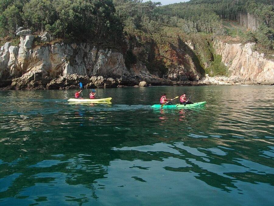 Des kayakistes sur une étendue d'eau calme, avec des falaises rocheuses en arrière-plan.