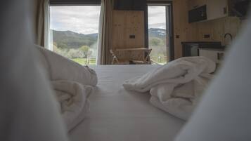 Un dormitorio con cama, un escritorio de madera y vistas al exterior.