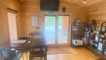 A wooden interior with a table and chairs, a television mounted on the wall, and a door labeled 'SALIDA'.