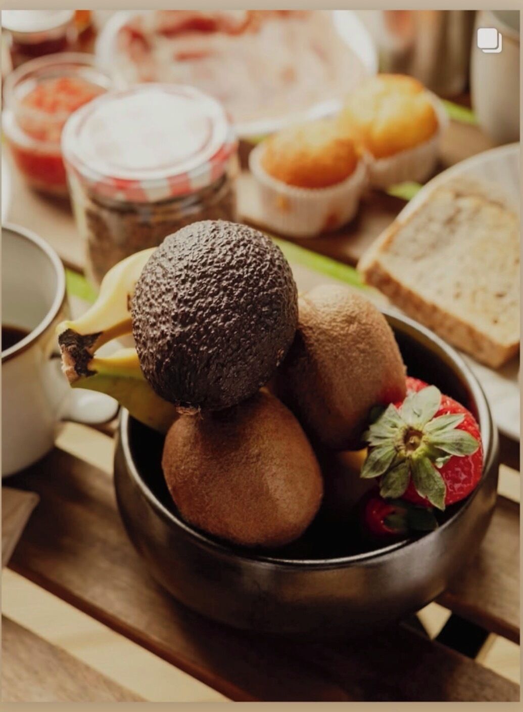 A bowl of kiwi fruits and a strawberry on a wooden table.