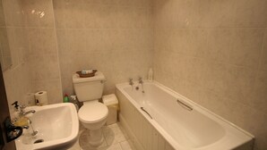 Kylpyhuone, jossa on pesuallas, wc ja kylpyamme.
