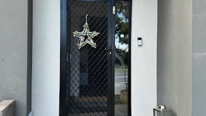 A modern building entrance with a black door, a star decoration, and a small step leading up to the door.