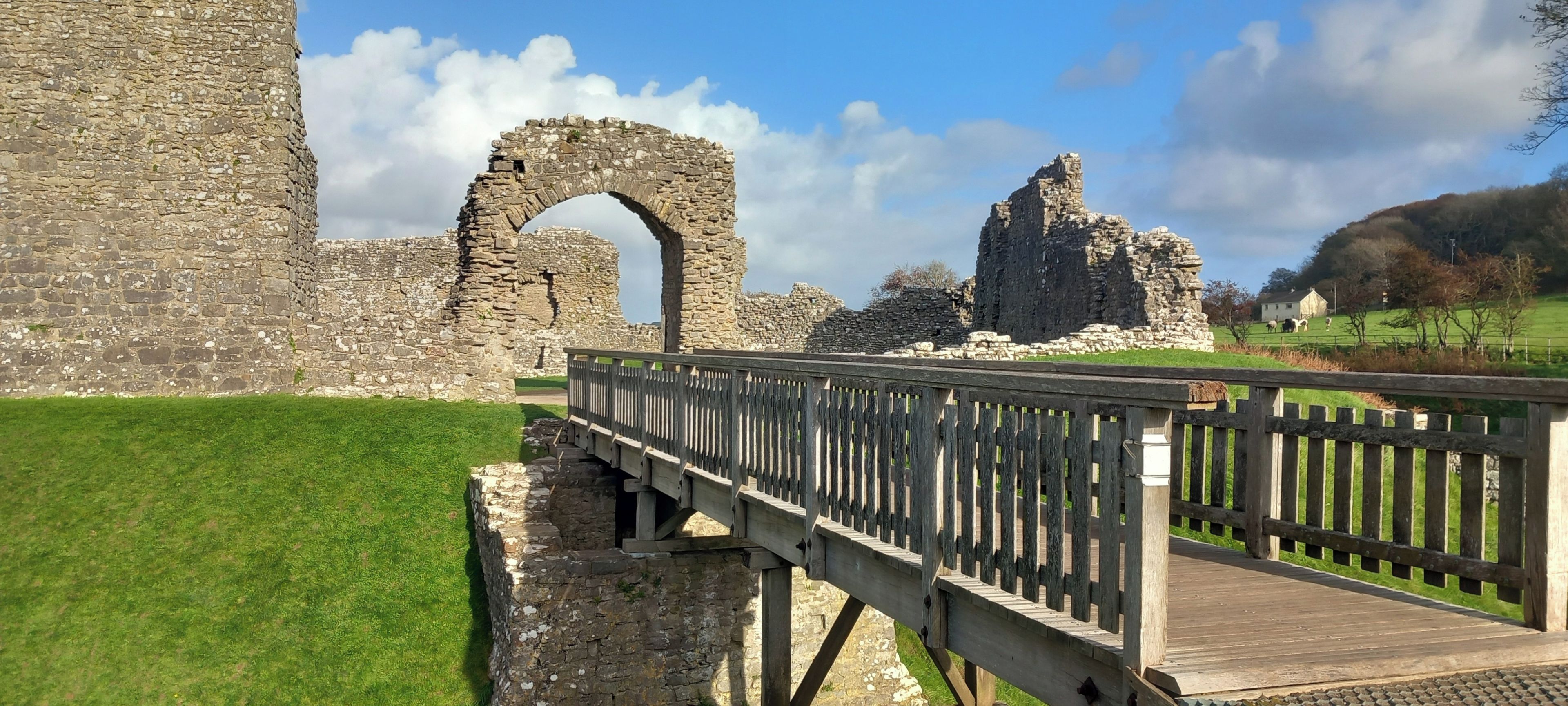 A stone bridge leading to ancient ruins with a clear sky.