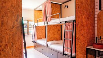 A bunk bed room with a wooden wall, a window, and a sink.