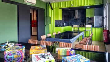 Een moderne keuken met groene kasten, een eethoek met een glazen tafel, en een brandblusser.