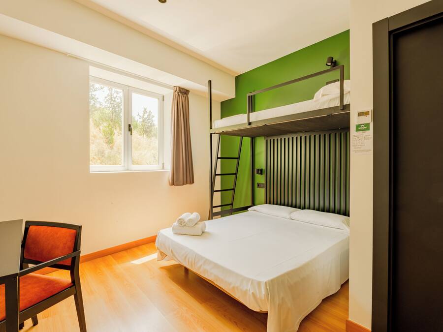 Una habitación con literas, un escritorio con silla, una ventana con cortinas y una puerta.