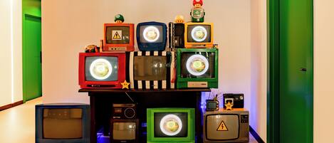A hallway with a collection of vintage televisions and electronic devices arranged on a shelf.