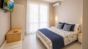 Een slaapkamer met een bed, nachtkastjes, een televisie en een airconditioning.