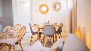 A dining area with a round table, wicker chairs, and two wall-mounted mirrors.