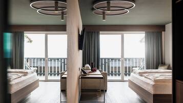 Ein modernes Hotelzimmer mit zwei Betten, einem Schreibtisch und großen Fenstern mit Blick auf den Balkon.