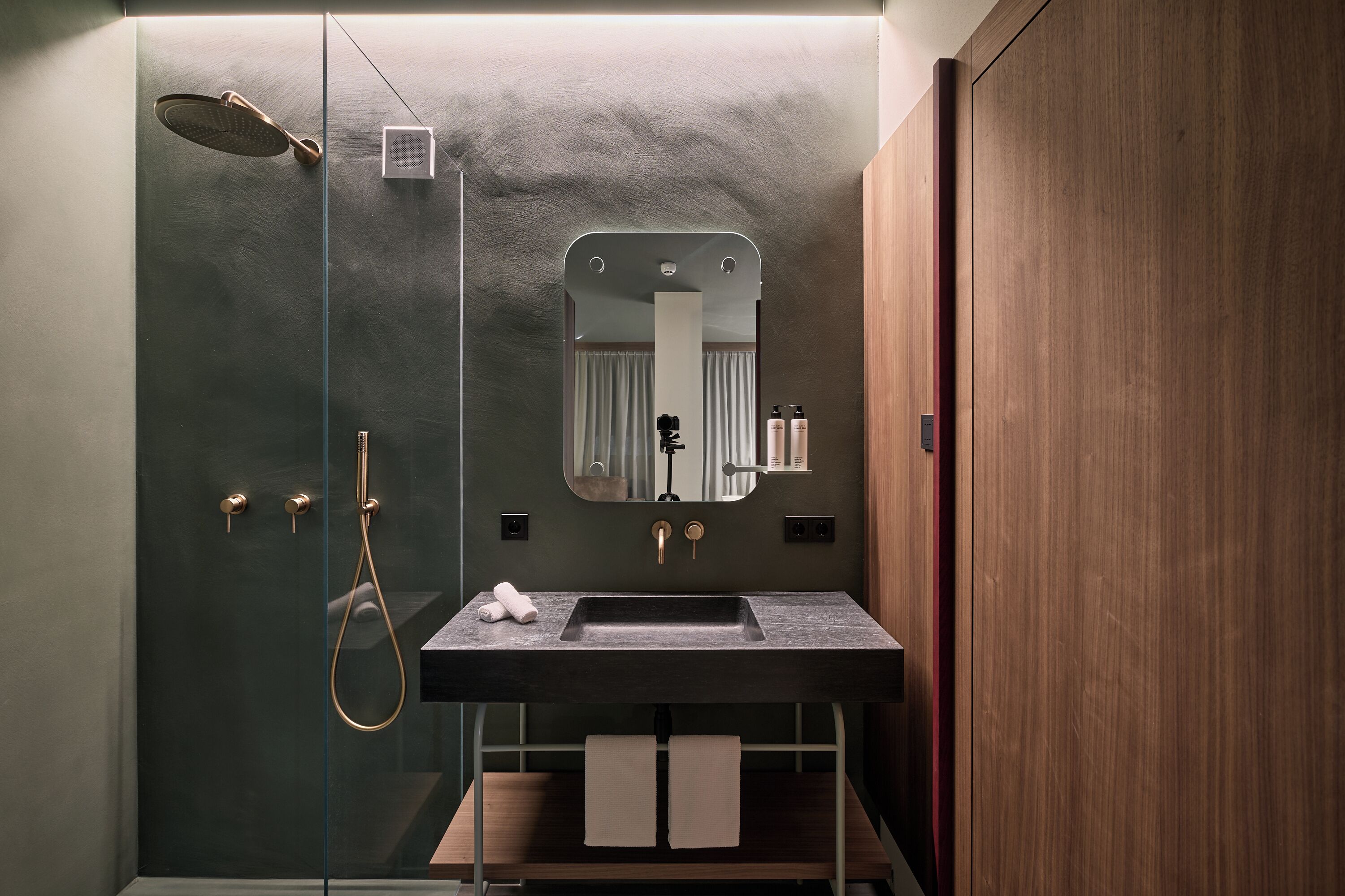 Un bagno moderno con doccia vetrata, un lavandino con specchio sopra e mobili in legno.