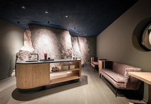 Un intérieur moderne avec un mur d’accent en pierre, un coin bar en bois et un canapé confortable.