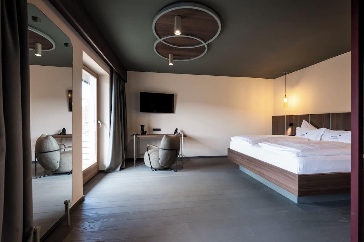Una habitación de hotel moderna con una cama de madera, un escritorio y una silla.