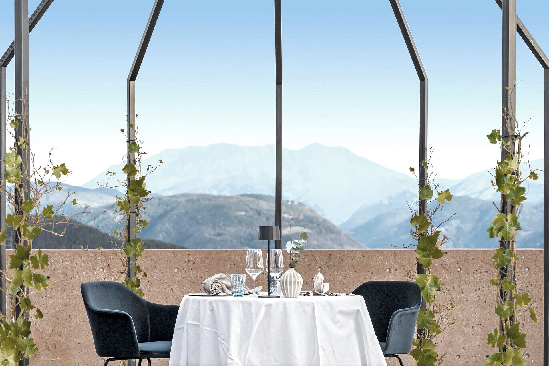 Mesa para dos con vista a la montaña, dos sillas y cielo despejado.