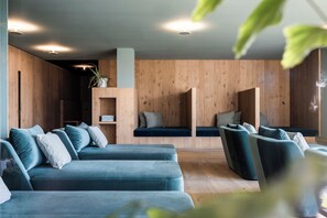 A modern interior with a wooden wall, a blue sofa set, and a small plant. - Hotel Belvedere- Fine Dining & SPA (San Genesio Atesino)