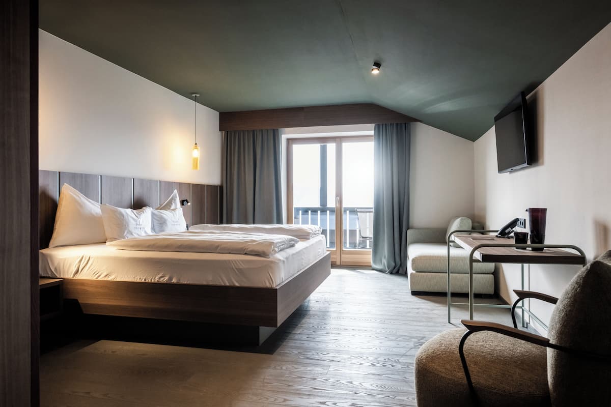 Una habitación de hotel moderna con una cama grande, un escritorio y una televisión.