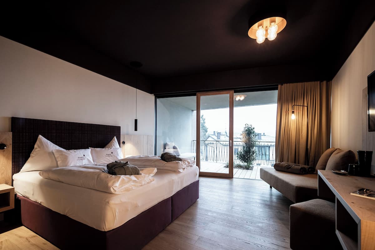 Una habitación de hotel moderna con una cama grande, un escritorio y un balcón con vistas.
