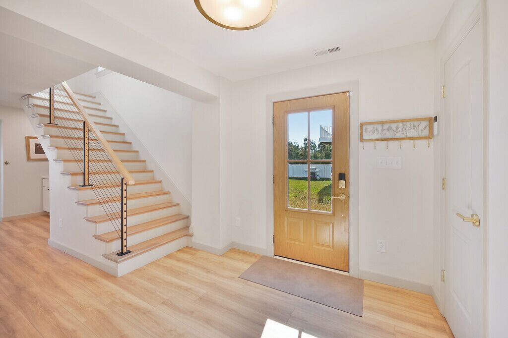 Een modern interieur met een houten trap, een houten deur met een ruit en een lijstwerkfoto aan de muur.