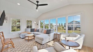 A spacious living room with a large sectional sofa, a round coffee table, and a ceiling fan.