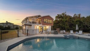 A two-story house with a swimming pool, outdoor furniture, and a fenced patio area.