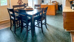 A kitchen with a dining table, chairs, wooden cabinets, a ceiling fan, and a window. - Beautiful farmhouse with horses, pet friendly & close to Prince Edward County. (Brighton)