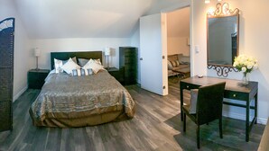 A bedroom with a large bed, bedside tables, a desk, and a chair. - Beautiful farmhouse with horses, pet friendly & close to Prince Edward County. (Brighton)